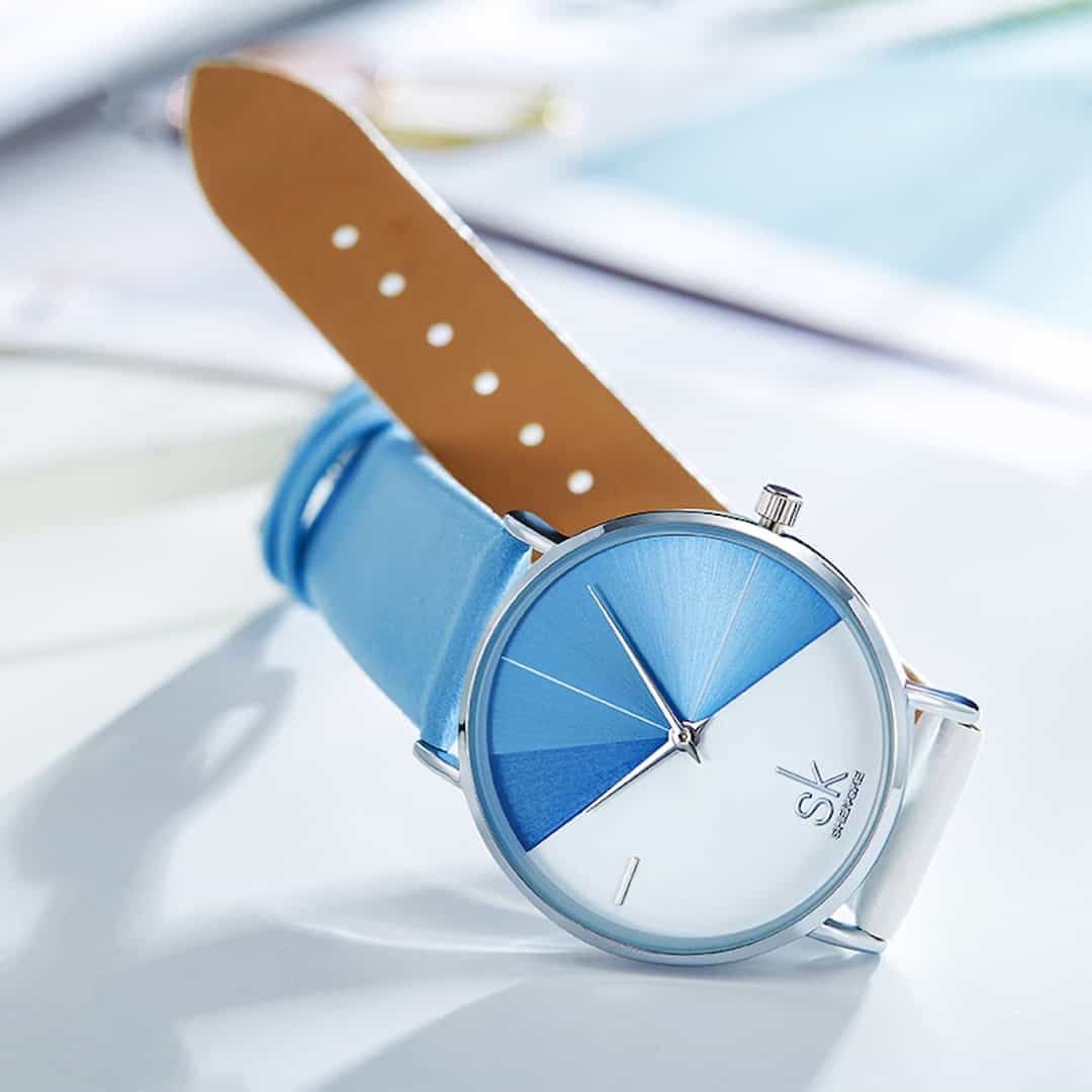Ženska ročna ura SK Shengke DuoTone Leather Blue s svetlim paščkom, prikazana na svetli površini.