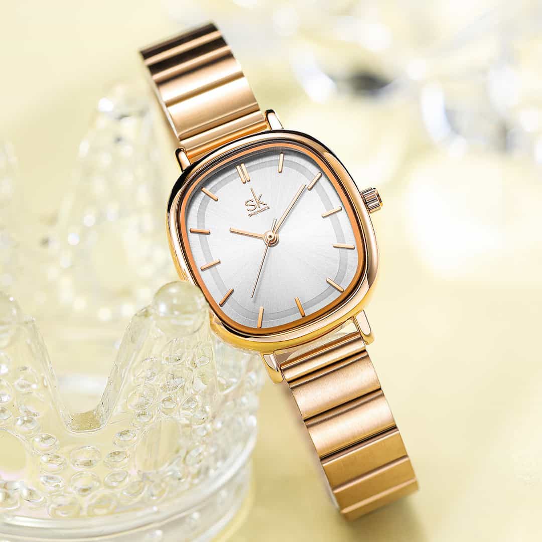 Ženska ročna ura SK Shengke Mystic Rose Gold ob dekorativni podlagi.