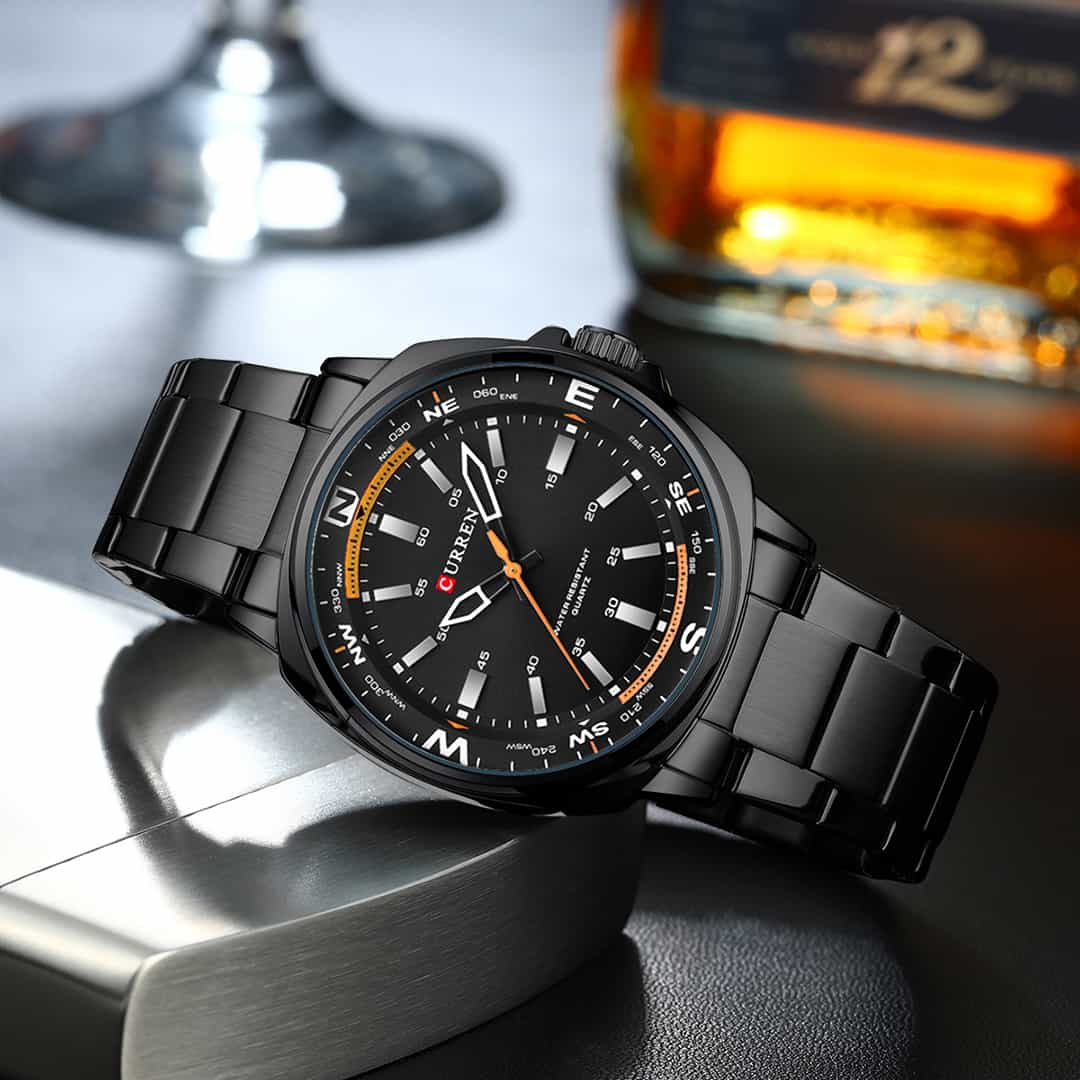 Moška ročna ura Curren Zenith Black v elegantnem ambientu ob steklenici.